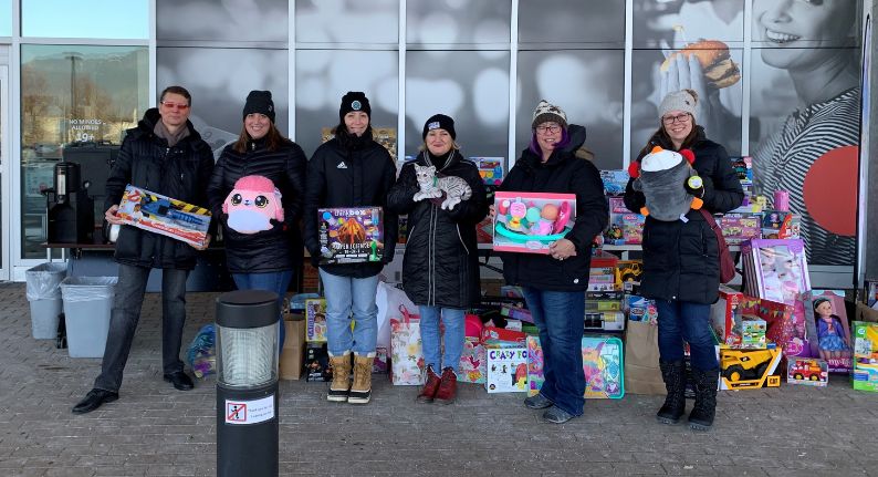 A group of people engaged in community involvement, standing in front of a building with toys.