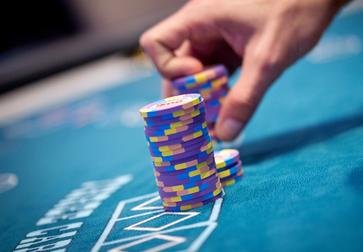 A person is holding a stack of Shorelines Casinos poker chips on a table.