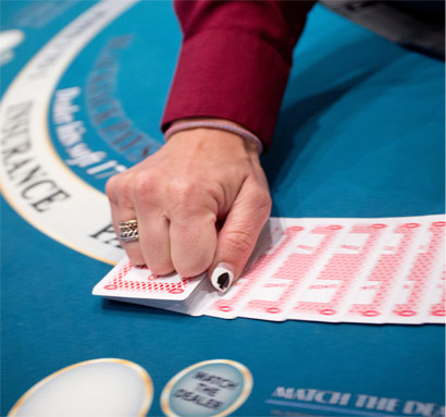 A Great Canadian Rewards member holding cards on a blackjack table.