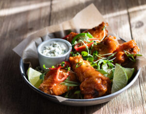 A bowl of chicken wings with dipping sauce.