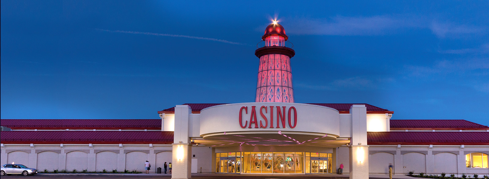 Casino New Brunswick stands illuminated against the darkened backdrop of light house at night.