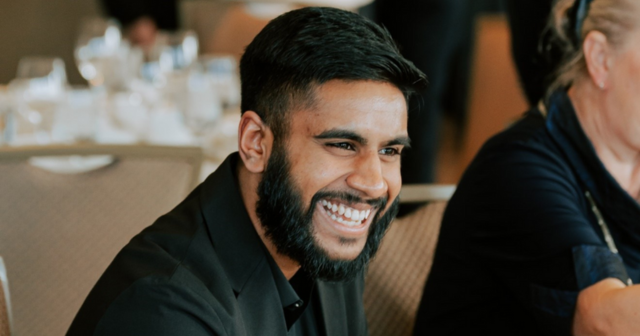 Invitee sitting in suit smiling with table settings in the background