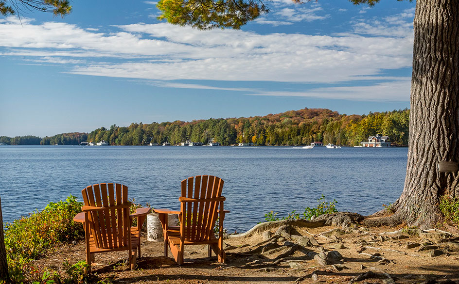 Staycation photo, two empty chairs in front of a beautiful lake in the fall.