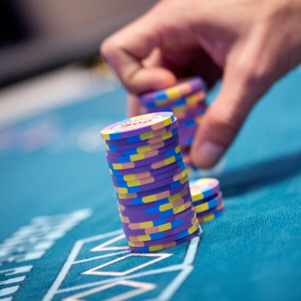 A person is holding a stack of Shorelines Casinos poker chips on a table.